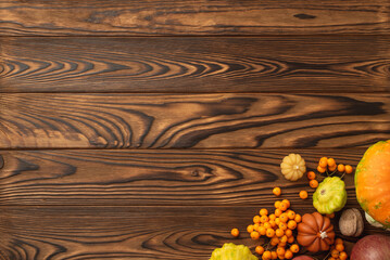 Autumn harvest concept. Top view photo of raw vegetables pumpkin pattypan squash walnut and rowan berries on isolated dark wooden table background with copyspace