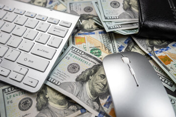 stack of many American dollars on a white laptop keyboard.