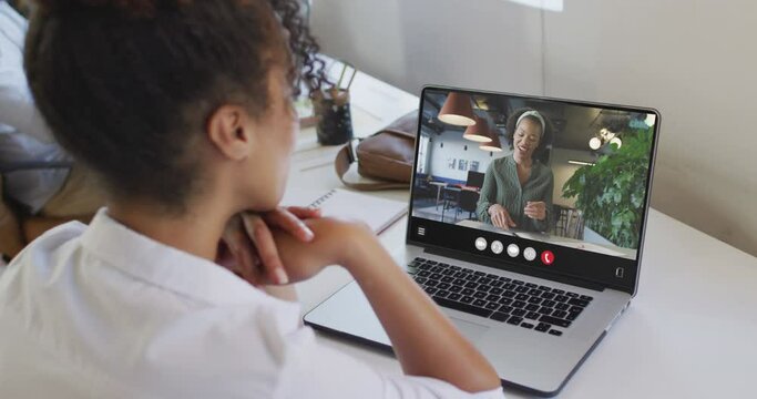 African american woman using laptop for video call, with business colleague on screen