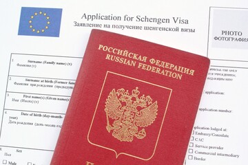 passport and Schengen visa application form in English and Russian language on background. Prohibition and suspension of visas for tourists to travel to European Union and Baltic States concept