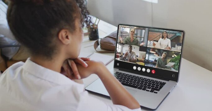 African american woman using laptop for video call, with diverse business colleagues on screen