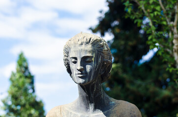 Primo piano di una statua bronzea di una donna dolente su una tomba del cimitero maggiore di Milano