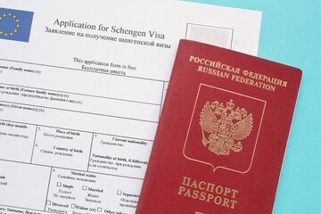 Schengen visa application form in English and Russian language and passport on blue background....