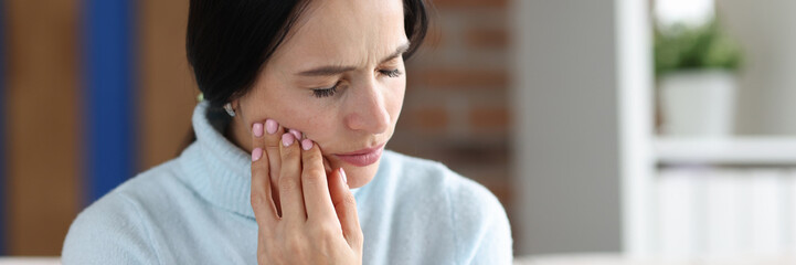 Woman holding her cheek in area of sore tooth