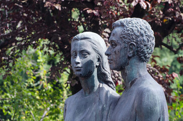 Primo piano della statua bronzea di un uomo e una donna  su una tomba del cimitero maggiore di Milano