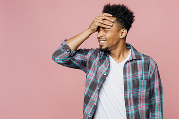Young sad man of African American ethnicity 20s he wear blue shirt put hand on face facepalm epic fail mistaken omg gesture isolated on plain pastel light pink background studio Tattoo translate fun.