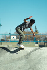Hispanic skate boarder doing trick at the top of skate park bowl