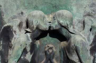 Fototapeta na wymiar Il bassorilievo bronzeo di due angeli che si baciano su una tomba dell cimitero maggiore di Milano
