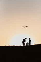 Silhouettes of a family flying a kite at sunset.