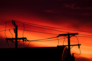 Silhouette of high voltage pole and orange blue sky background on everning day