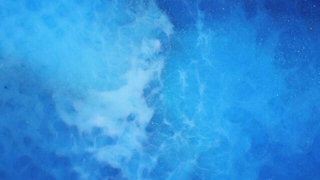 Abstract liquid artistic background, metallic sparkling blue, green, turquoise water. Macro video of shiny and iridescent ink particles.