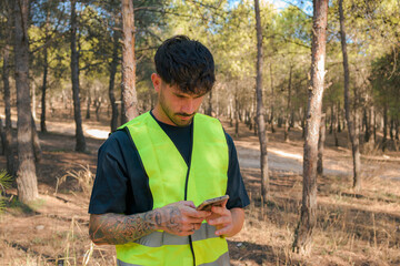 Man in safety reflective vest looks at his mobile phone
