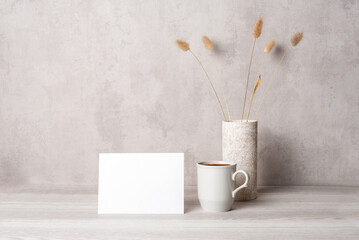 Template with photo frame on a wooden table. Bouquet of Lagurus. Sunlight from the window.