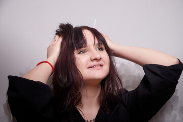 Fototapeta premium Young elegant woman in trendy black clothes with white wings suffers and screams. Brunette model in nice dark dress posing in studio in fashion lookbook as angel with emotions. Alone girl in the room