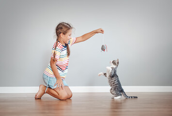 Cute girl playing with her little kitten at home
