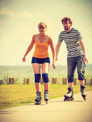 Obraz premium Young couple on roller skates riding outdoors