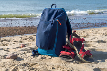 Backpack and sandals against the backdrop of nature. Walking along the seashore.