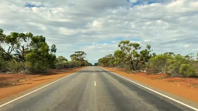 Roadtrip alone in Western Australia. Empty road in the desert with red sand