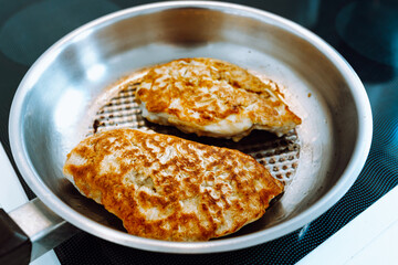 Fried chicken breast in batter and breadcrumbs in grill pan, cooking Austrian schnitzel