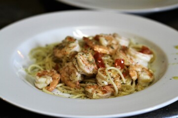Spaghetti alla olio with shrimp in white shallow bowl