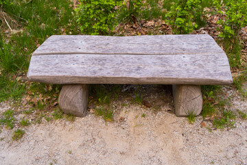 a wooden bench made of pieces of timber on the ground with green grass and stones front photo the bench is not covered with anything dry