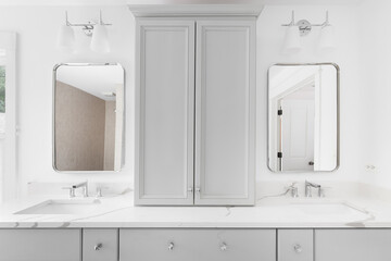A luxury bathroom's grey vanity cabinet with a white marble countertop, chrome faucets, and mirrors.