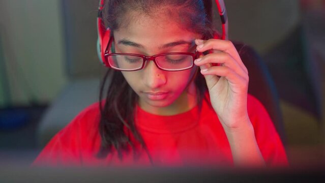 tired exhausted girl kid rubbing eyes by removing eyeglasses while playing online video game at home - concept of technology addiction, eye irritation and gaming tournament.