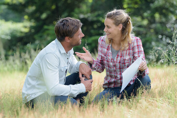 couple holding a piece of paper sitting on the grass