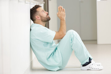 handsome surgeon doctor man praying with hands together