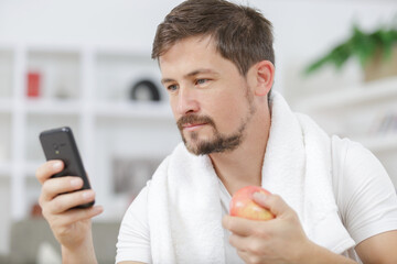 man wearing gym clothing looking at mobile phone