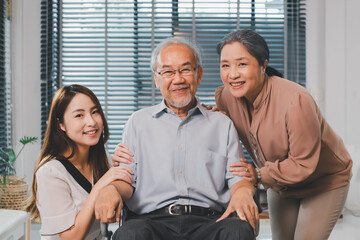 Happy family. Asian young daughter and mother support senior older man. Beautiful girl help and take care of elderly mature grandpa patient doing physical therapy for health in living room in house.
