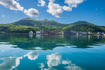 鏡のように青空、白い雲、有珠山、温泉街を映す洞爺湖面