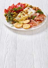 savory baked brie with crackers, salami, nuts, ham