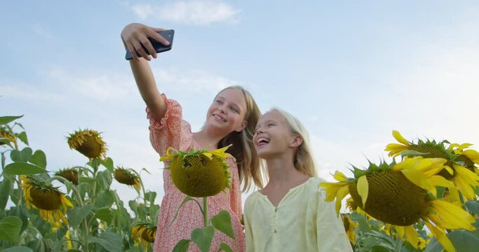 Pretty girl holding mobile phone in hands taking photo in garden at sunny day. Relaxed girl making selfie phone in field