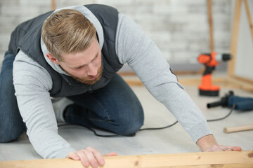 craftsman measuring a plank of wood with a spirit level