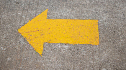 Yellow arrow symbol painted on asphalt on the road. Asphalt road yellow marking. Direction arrow