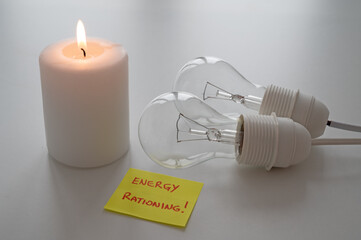 Lit candle, next to two unlit bulbs, with a yellow note with the text 