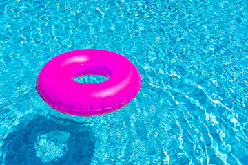 Violet ring floating in blue swimming pool. Inflatable ring, rest concept