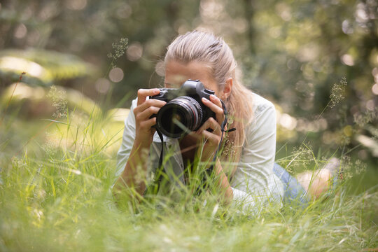 girl photographer taking pictures laying on long grass