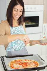 beautiful woman wearing apron preparing a pizza