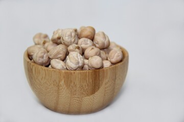 Chickpeas (Cicer arietinum), in a wooden bowl, isolated on a white background, selective focus. It is also known by the names: Gravanço, Herbanzo, Chicken Pea or Bengal Pea or Duck Grain.