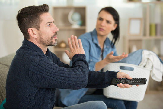 Woman With Washing Being Silenced By Husband Watching Tv