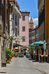 A narrow street in the old town of Grosseto with the bell tower of the Church of St Francis in the...