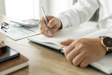 Business man writing a business investment plan, man wearing white shirt Work on the desk in the office