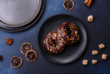 Pastries concept. Donuts with chocolate glaze with sprinkles, on a dark concrete table