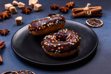 Pastries concept. Donuts with chocolate glaze with sprinkles, on a dark concrete table