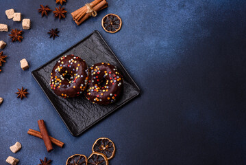 Pastries concept. Donuts with chocolate glaze with sprinkles, on a dark concrete table
