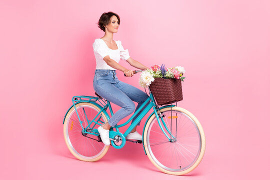Full length photo of shiny cute girl dressed white blouse driving bicycle isolated pink color background