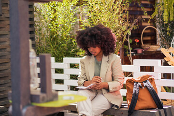 Pensive black businesswoman making notes on street