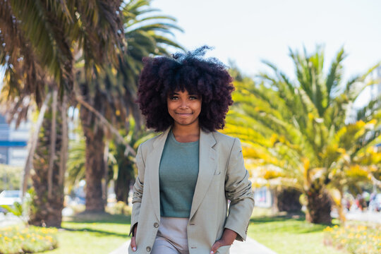 Positive black businesswoman walking in park
